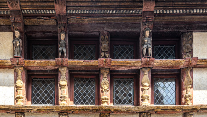 Geschnitze Holzfiguren umrahmen mittelalterliches Fenster in Vitré