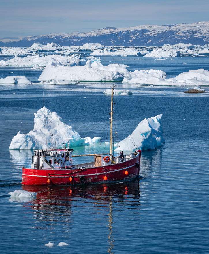 Rotes Fischerboot zwischen Eisbergen